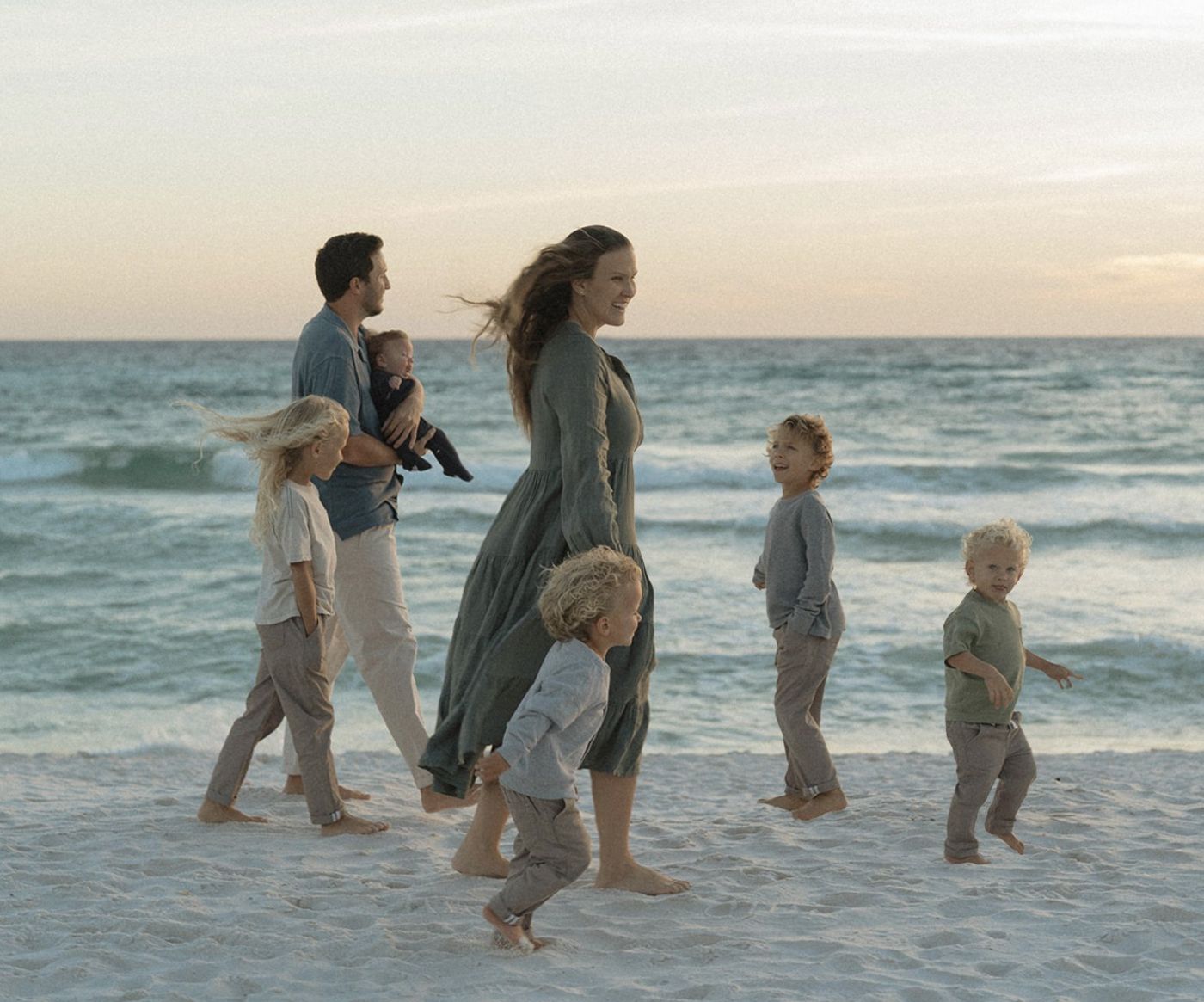 Landon and Kara walking on the beach at sunset with their five boys