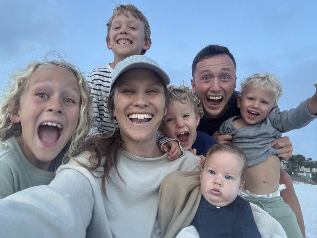 Landon, Kara, and their five boys laughing together in a beach selfie
